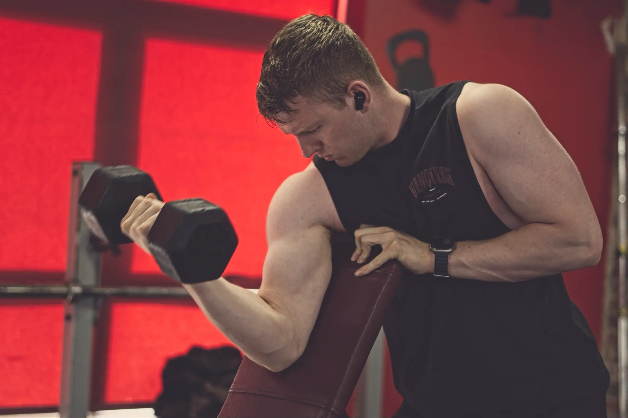 A member doing bicep curls against the red studio wall