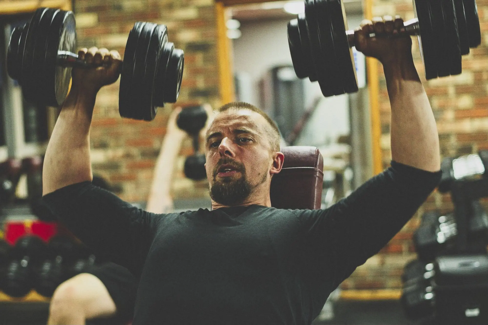 A member doing dumbbell shoulder presses in the free-weights area